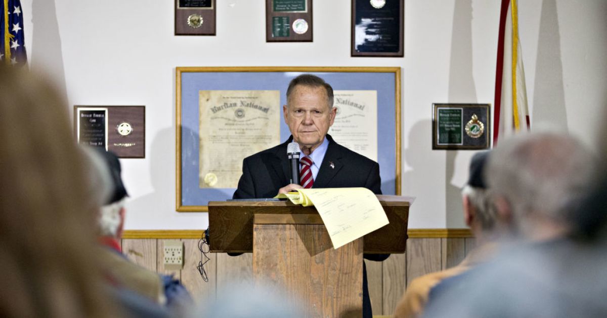 Moore Tries to Play to the Crowd While Avoiding Cameras at Rally